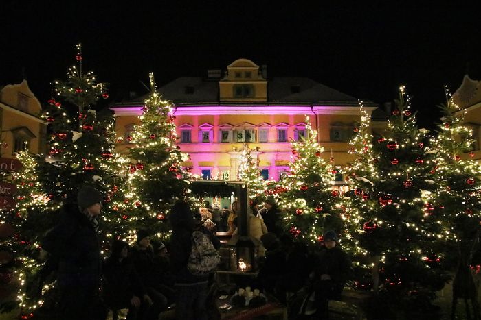 Schloss Hellbrunn lit up at night, with fir trees standing in the courtyard.