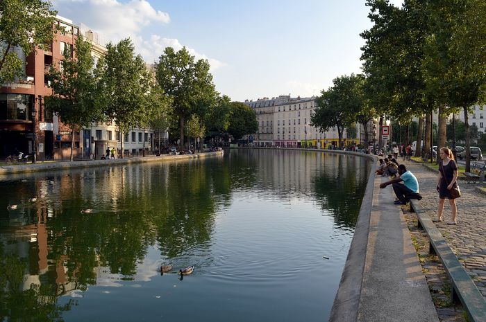 The Canal Saint-Martin with an iron footbridge and a lock. On Sundays and public holidays the quays close to cars and the quarter belongs to pedestrians.